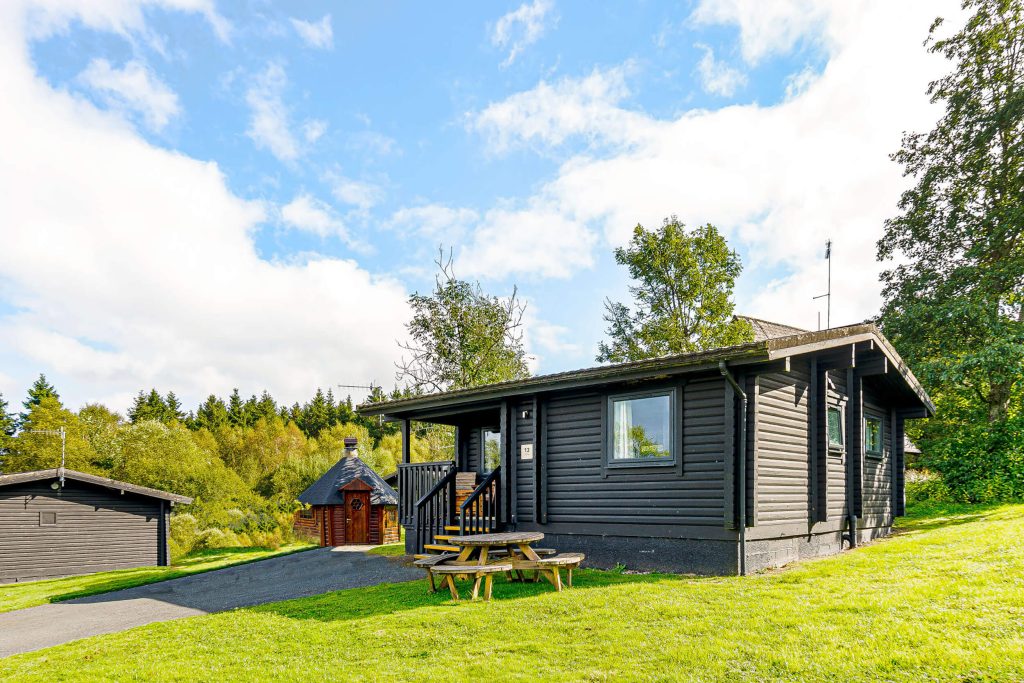 Elf Kirk BBQ at Kielder Waterside. View of single story lodge with BBQ hut