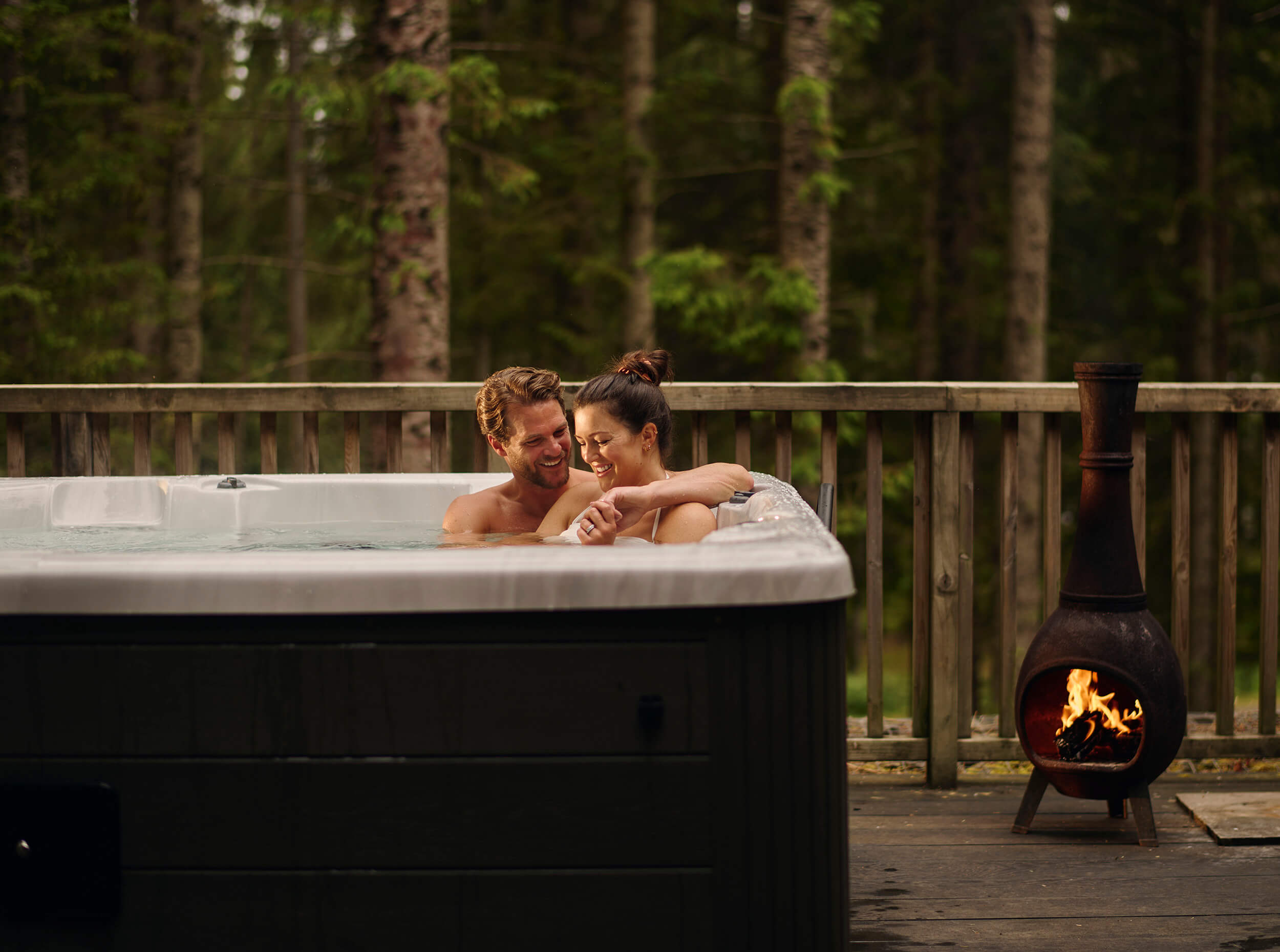 Couple cuddled up in a Kielder Waterside hot tub on their romantic escape in the Northumberland forest.