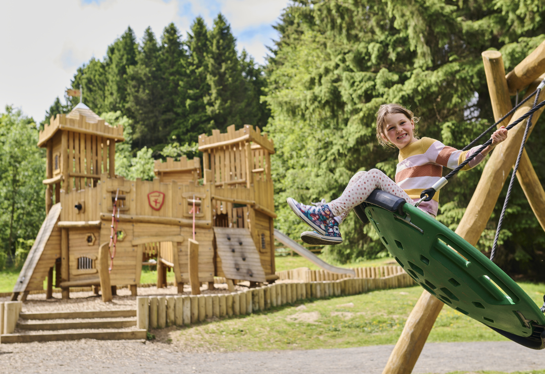 Facilities - Play Park - Child swinging in front of castle